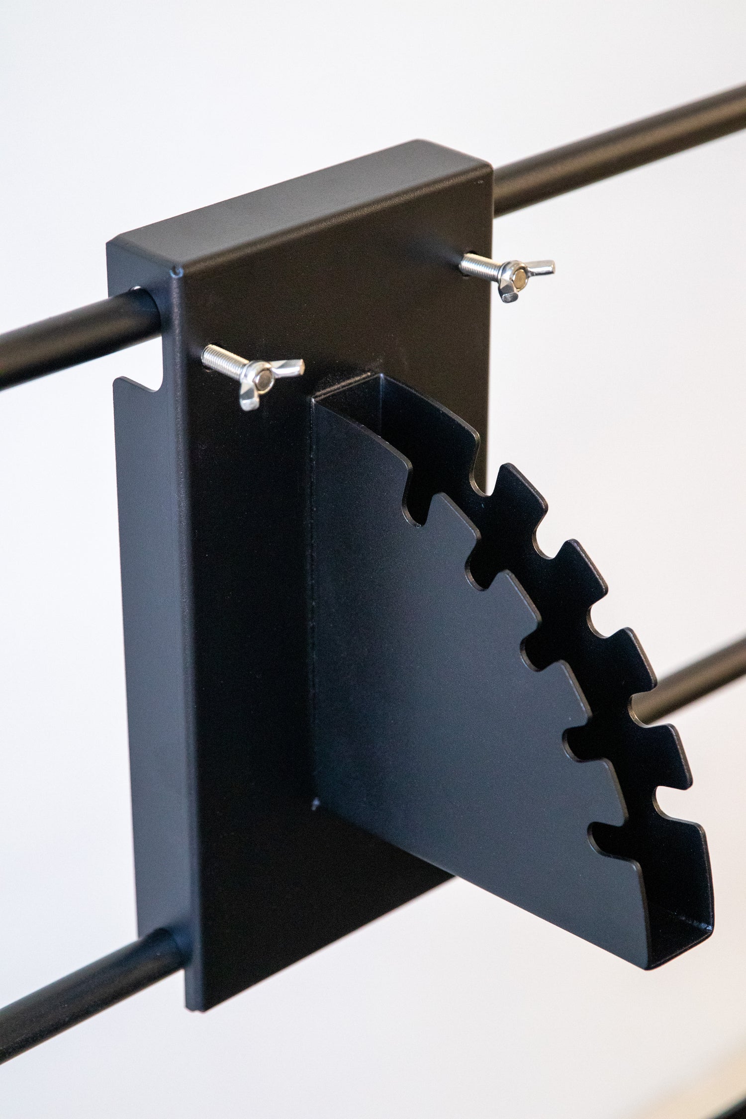 Metal bracket with a serrated edge on a white background. Terra Grills pin attachment system for height adjustment of cooking accessories