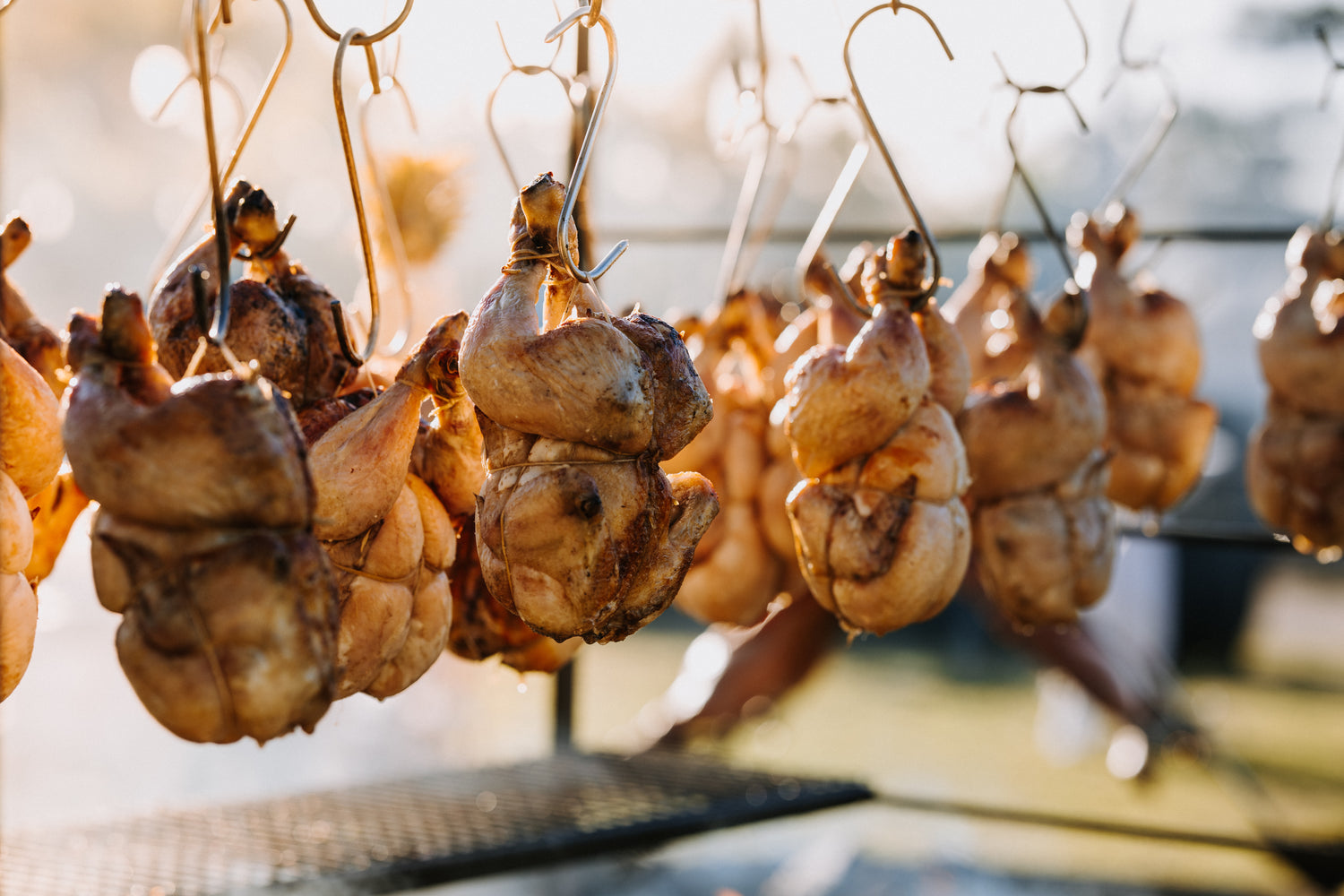 Chickens hanging on hooks with a blurred background cooking on the Argentinian style bbq assado grill style