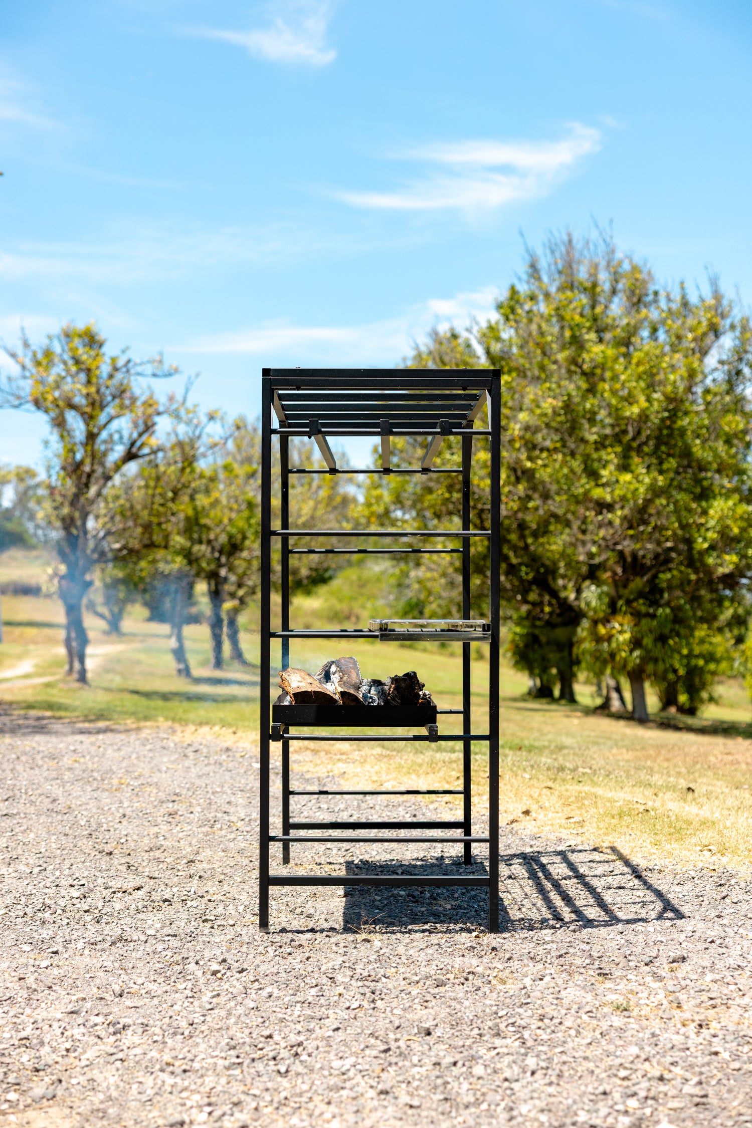 Angled side view of the Portico Small Argentine Parrilla grill frame. Terra Grills Portico Small open fire grill detail of adjustable cooking grates